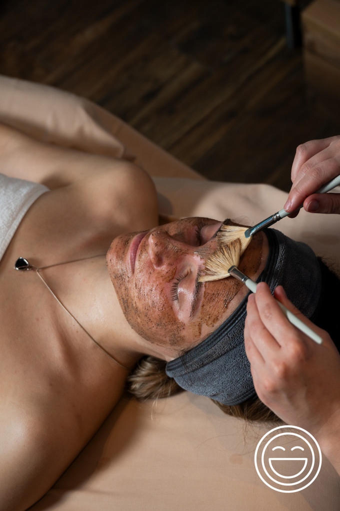 eine Frau die mit Pinseln eine Maske aufgetragen bekommt