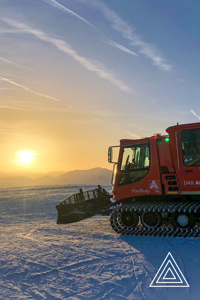 Pistenbully im Schnee vor Sonnenuntergang