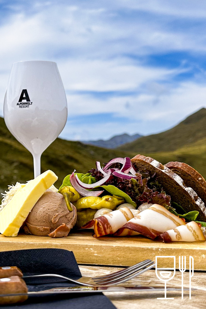 ein Glas Wein neben einer Jausenplatte