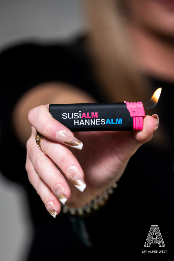 schwarz - pinkes Feuerzeug mit Susi Alm & Hannes Alm Logo