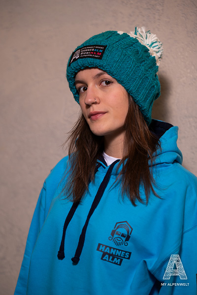 blue wool hat with white pom-pom & Alpenwelt, Susi Alm, and Hannes Alm logo patch