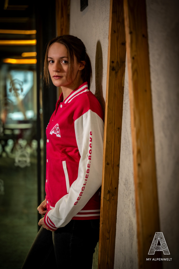 Pink and white college jacket: Alpenwelt logo on the front left, Bergliebe.Rocks lettering on the left sleeve