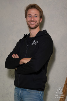 Schwarze Reißverschluss Jacke mit Kapuze. Hannes Alm und Susi Alm Logo vorne Links