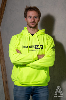Neongelber Hoodie Aufdruck Vorne: Hannes Alm & Zillertal Arena. Aufdruck linker Ärmel: Alpenwelt Resort Logo